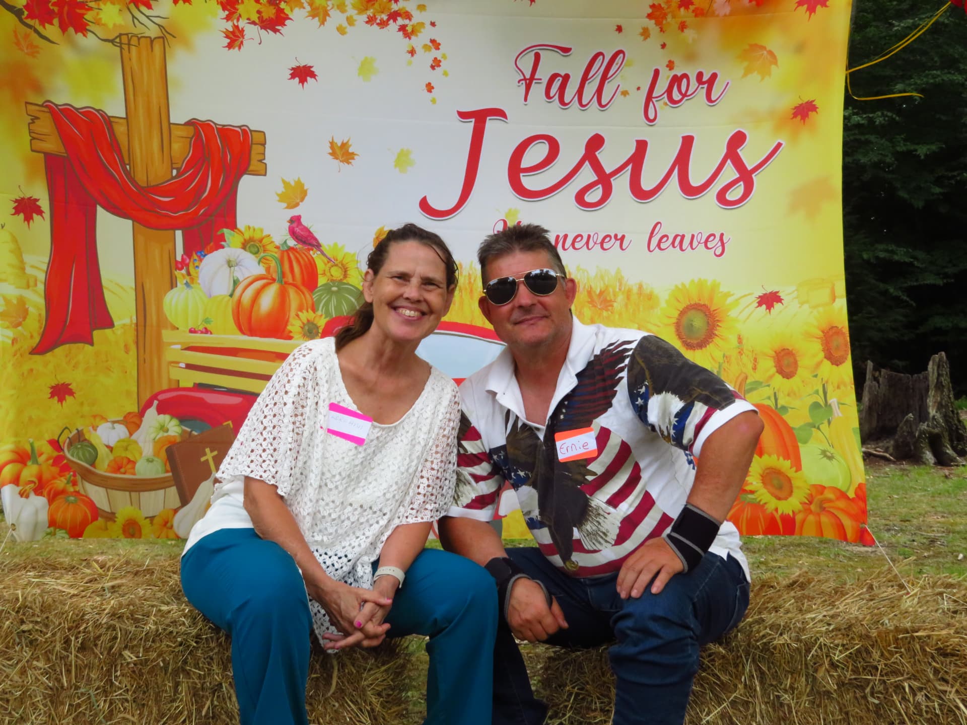 Two members posing close together at the Fall for Jesus backdrop