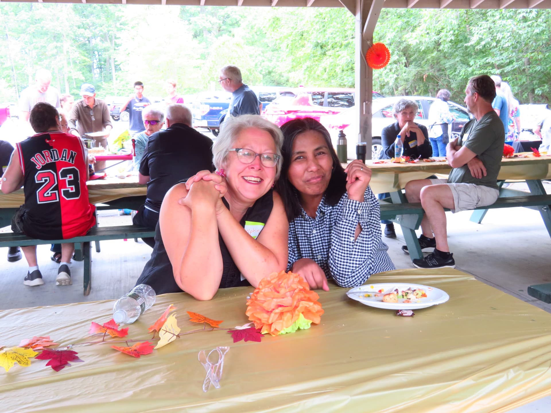Two friends smiling together at a decorated picnic table