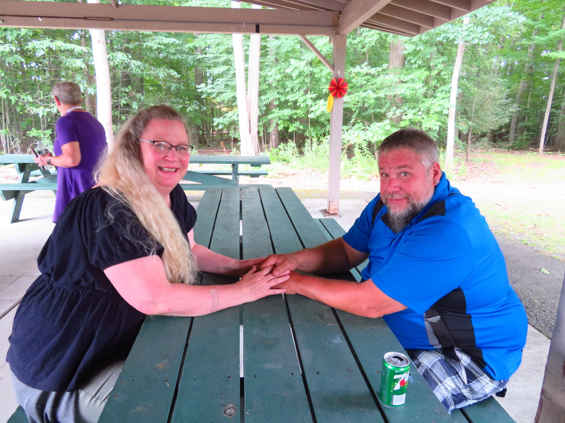 A couple holding hands across a picnic table under the pavilion