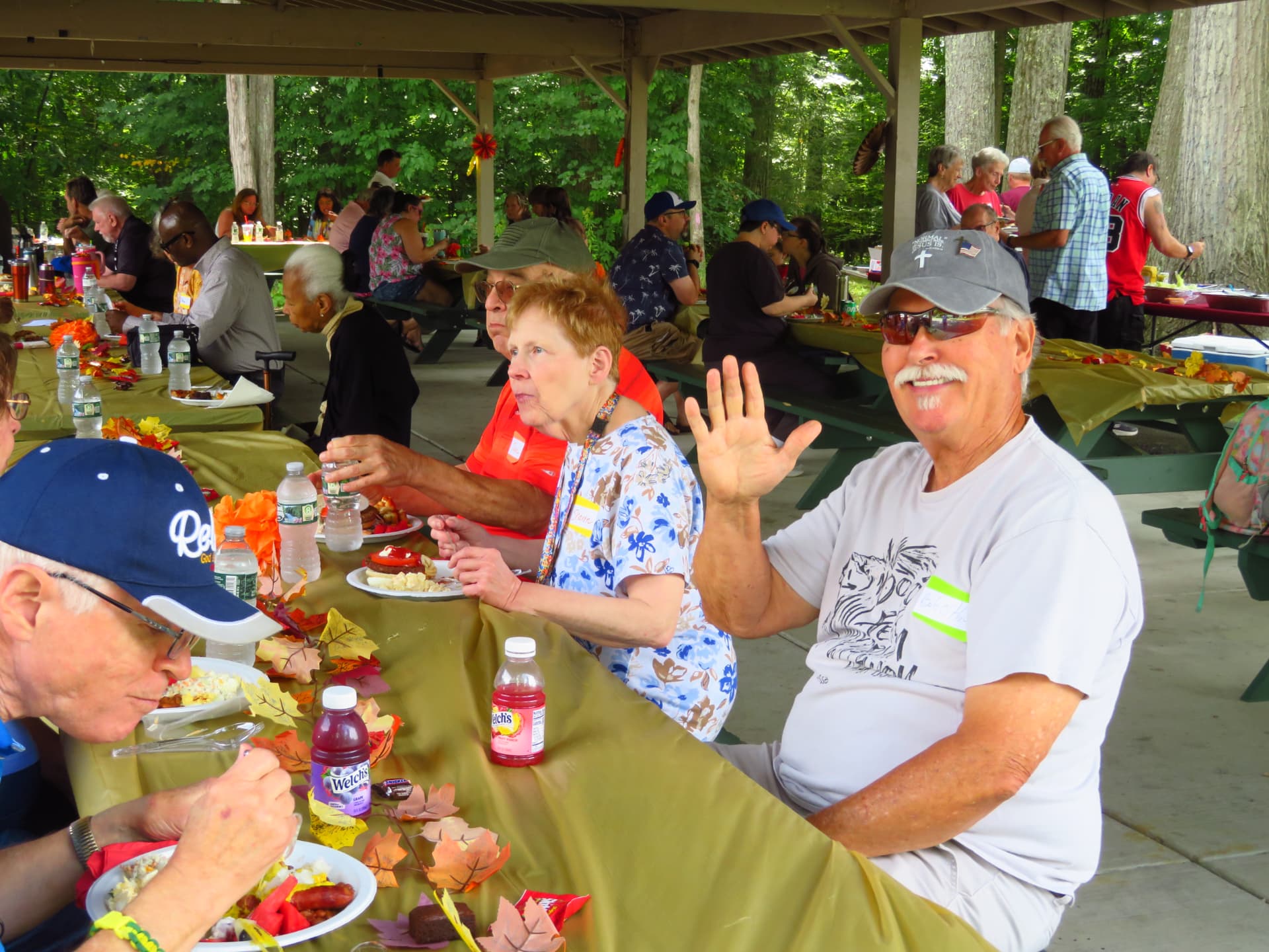 Church family waving while enjoying lunch at the long picnic tables