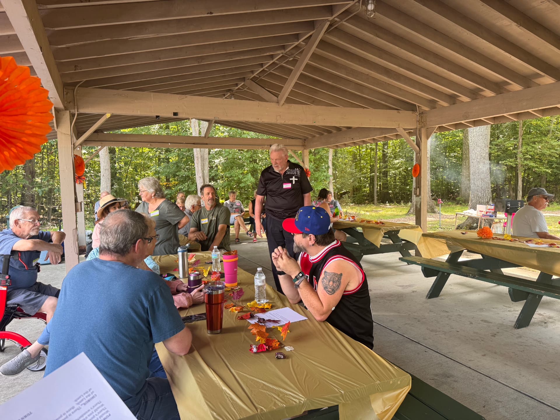 Members visiting around a picnic table decorated with fall leaves