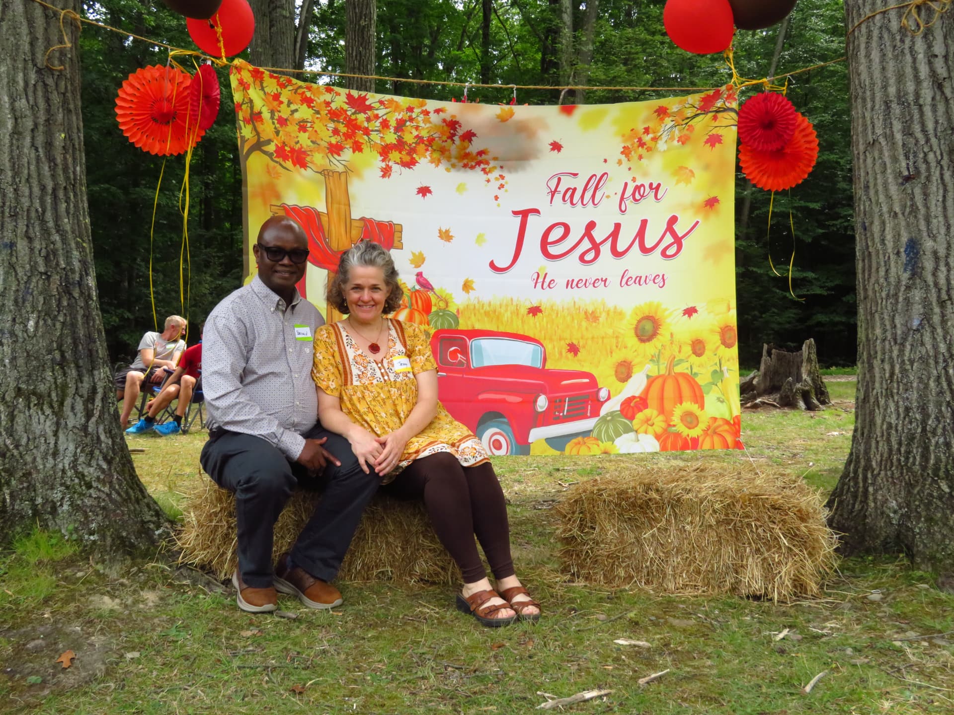 A couple smiling on hay bales at the photo backdrop